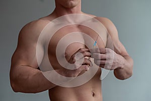 Close-up of a male torso. Unrecognizable shirtless bodybuilder man puts himself an injection of testosterone. Faceless