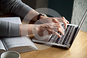 Close up of male typing on laptop studying in cafe