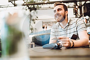 Close up of male using credit card contactless technology and smartphone for paying in restaurant