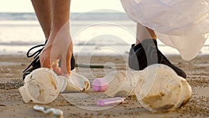 Close up of male volunteer collect and picking up garbage on the beach. Man cleans up coastline from plastic trash -