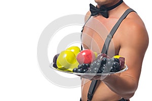 Close-up, a male waiter with a bare torso, holding a tray of fruit in his hand, on a white background, there is a place for the