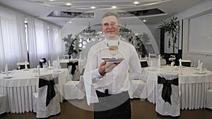 Close-up of a male waiter holding a plate with a cup of latte in a restaurant.