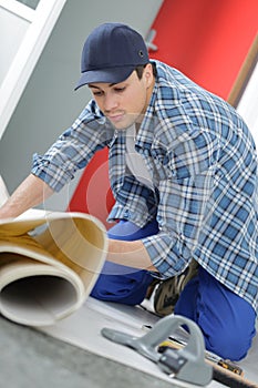 Close up male worker unrolling carpet in office photo