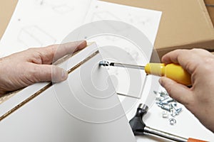 Close Up Of Man Assembling Flat Pack Furniture With Screwdriver photo