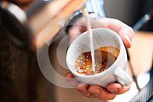 Close Up Of Man Barista Hands Pouring Steamed Milk In Homemade Coffee. Making Beautiful Latte Art. Stay Home Concept