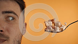 Close-up of a man with a beard and a caesar salad on forks. A man licks his lips, really wants to eat Caesar salad with