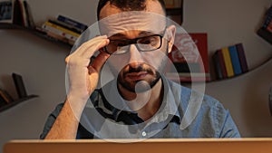 Close-up, man with beard sittin working with laptop from home.