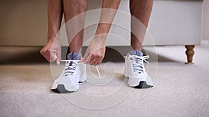 Close Up Of Man In Bedroom At Home Putting On Fitness Clothing And Trainers Ready For Exercise