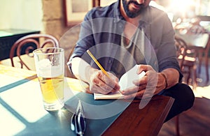 Close up of man with beer and notebook at pub