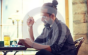 Close up of man with beer and notebook at pub