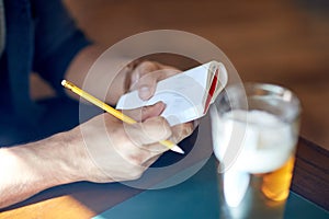 Close up of man with beer and notebook at pub