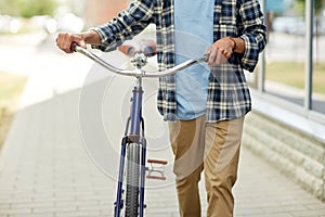 Close up of man with bicycle walking along city