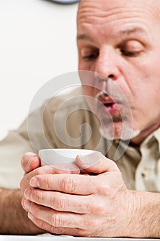 Close up of man blowing into cup