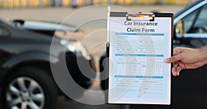 Close up of a man car insurance agent inspecting damaged car with insurance claim form. Insurance concept.