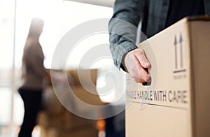 Close Up Of Man Carrying Removal Box As Couple Move In Or Out Of New Home