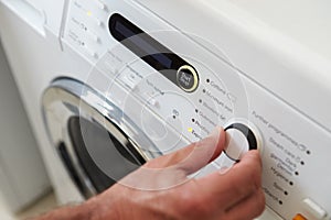Close Up Of Man Choosing Cycle Program On Washing Machine