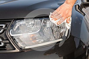 Close-up of man cleaning car headlight