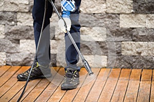 Close up of a man cleaning terrace with a power washer - high water pressure cleaner on wooden terrace surface