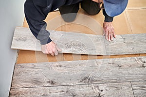 Male worker hands installing laminate floor in apartment.