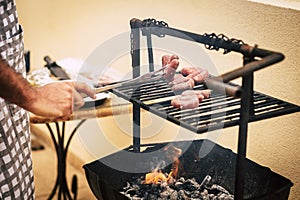 Close up of man cooking on bbq grill outdoor. Home celebration and meal food preparation with fire. Outdoor kitchen concept.