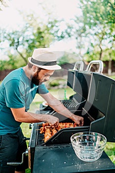 Close up of man cooking on grill,  having beers and cooking on garden barbecue. Lifestyle, leisure concept
