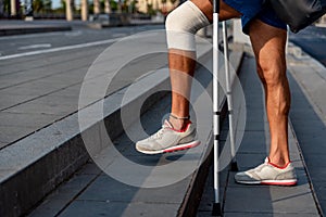 Close up of man with crutches climbing stair steps