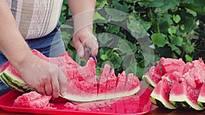 Close-up man cuts a slice of watermelon into equal parts.