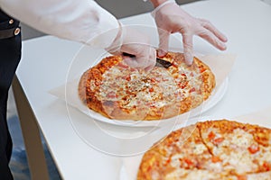 close-up. man cutting large margherita pizza on the table with appetizers