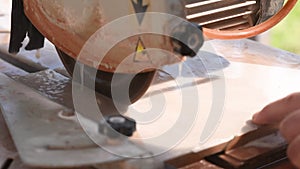 Close-up of a man cutting tiles and granite with an electric circular saw and applying water to it