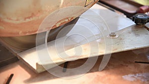 Close-up of a man cutting tiles and granite with an electric circular saw and applying water to it