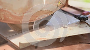 Close-up of a man cutting tiles and granite with an electric circular saw and applying water to it