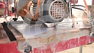 Close-up of a man cutting tiles and granite with an electric circular saw and applying water to it