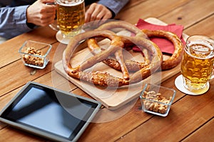 Close up of man drinking beer with pretzels at pub