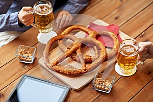 Close up of man drinking beer with pretzels at pub