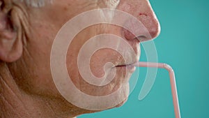 Close-up of a man drinking juice or a cooling cocktail through a straw, profile view. Beverage