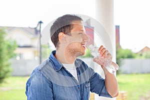 Close up of a man drinking water from bottle outdoor. Man refreshing himself. Thirsty man drinking water from a plastic bottle in