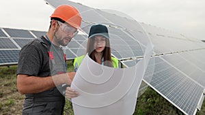 Close up man engineer in hard hat and inspector engineer woman learning the paper plan construction of solar panels