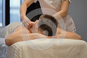 Close-up of man enjoying in relaxing shoulders massage . Man relaxing on massage table receiving massage