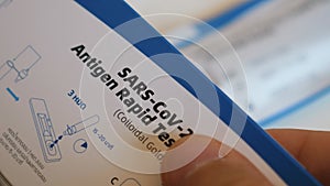 Close up of man examines box with Sars-Cov-2 antigen rapid test with instruction