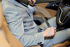 Close up of man fastening seat safety belt in car