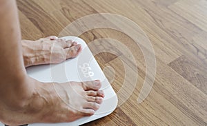 Close up a man feet on body scale checking body weight, dieting and lose weight concept