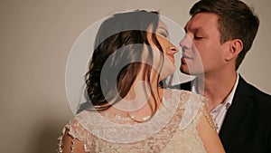 Close-up of a man gently embracing and kissing a girl on a white background.