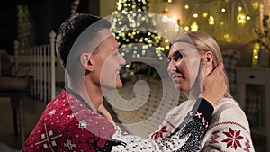 Close-up of a man gently stroking the head of his girlfriend near Christmas tree