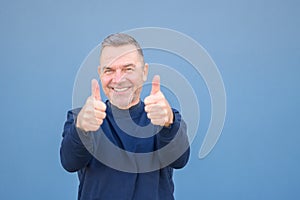 Close up of a man giving a double thumbs up gesture with a beaming smile
