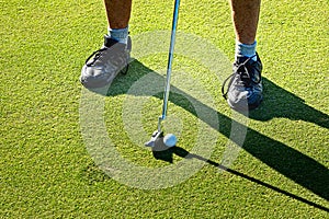 Close up of a man on the green putting the ball, playing golf