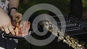 Close-up of man grilling pieces of red meat. Stock footage. Man cooks two pieces of beef or pork on grill. Man cooks