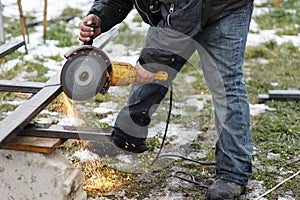 Close up of man grinding metal with circular grinder disc and electric sparks. Worker cutting metal with angle grinder for welding