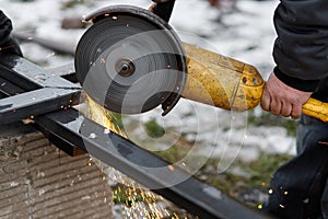 Close up of man grinding metal with circular grinder disc and electric sparks. Worker cutting metal with angle grinder for welding
