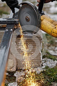 Close up of man grinding metal with circular grinder disc and electric sparks. Worker cutting metal with angle grinder for welding