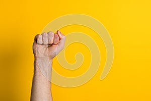 Close up man hand fist over a yellow background. winner and power sign